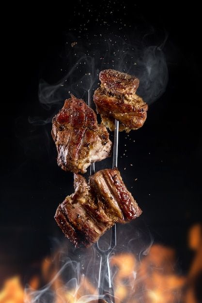 Garfo com pedaços de carne assada deliciosa em fundo preto _ Foto Premium